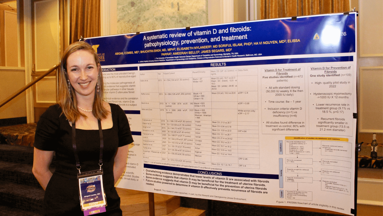 Woman standing next to a scientific poster on vitamin D and fibroids.